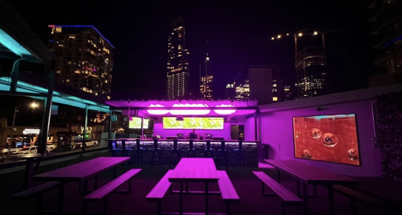 Willow's rooftop at night under magenta lighting with the downtown Austin skyline behind